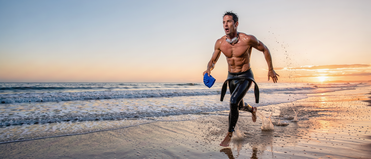 Triathlete running out of the ocean at sunrise